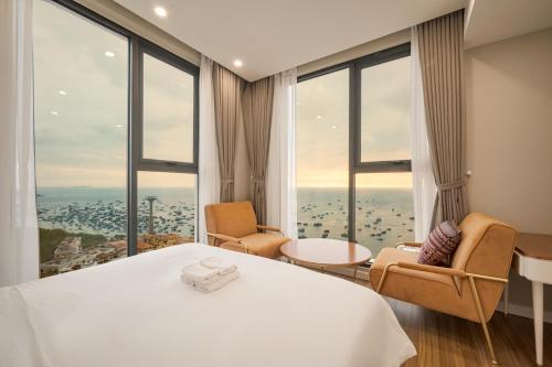 a hotel room with a large bed and two chairs at La isla Apartments & Villas - Sea View & Fireworks Phu Quoc in Phu Quoc