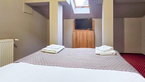 a bedroom with a bed with two towels on it at Pensiunea Bucura in Călimăneşti