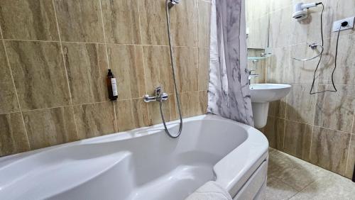 a bathroom with a tub and a toilet and a sink at Pensiunea Bucura in Călimăneşti