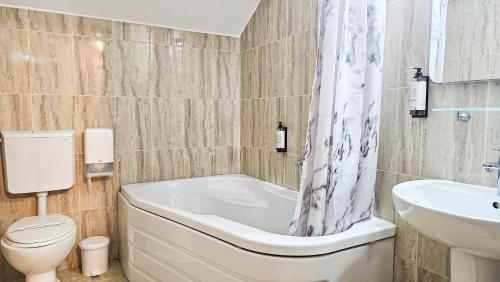 a bathroom with a tub and a toilet and a sink at Pensiunea Bucura in Călimăneşti
