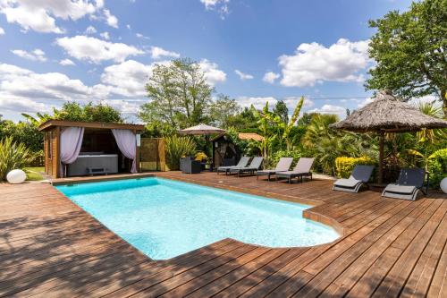 a swimming pool on a wooden deck with chairs and umbrellas at Gîte & Chambres d'Hôtes - Le Petit Bali in Saint-Pandelon