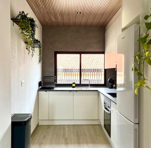 a kitchen with white cabinets and a large window at Apartamento boutique luminoso a 5 min del metro in Bétera