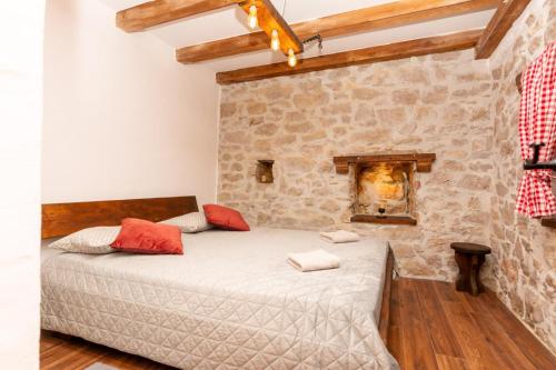 a bedroom with a bed in a stone wall at Kuća za odmor Niko in Škabrnje