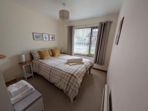 a bedroom with a bed with yellow pillows and a window at 8 Jib Park, Orkney Islands in Finstown