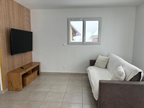 un salon avec un canapé et une télévision à écran plat dans l'établissement Jolie maison à la montagne, à Les Déserts