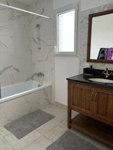 une salle de bain avec une baignoire, un lavabo et un miroir dans l'établissement Jolie maison à la montagne, à Les Déserts