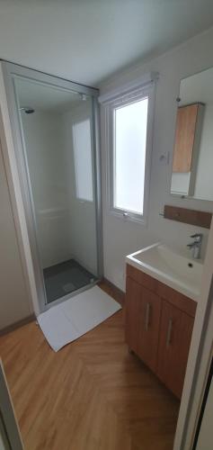 une salle de bain avec un lavabo et un miroir dans l'établissement MH 148, camping bois dormant, 2ch, 4 pers, à Saint-Jean-de-Monts