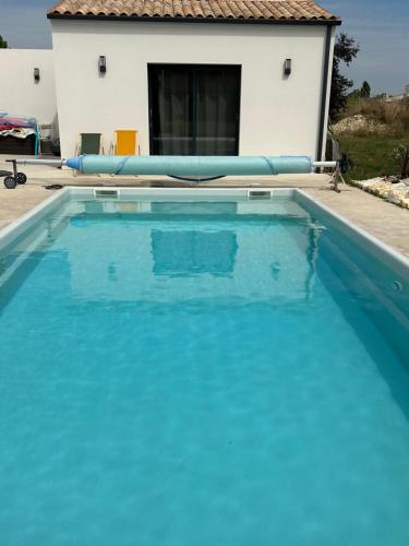a large blue swimming pool in front of a house at Love room in Gémozac