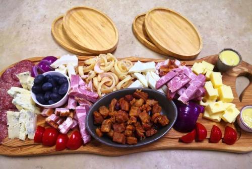 a wooden cutting board filled with different types of food at Casa Iustin in Moroeni