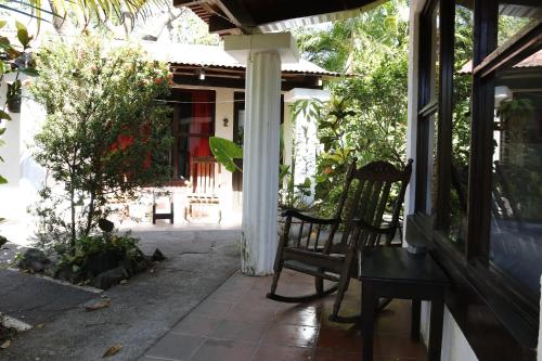 a porch of a house with a chair and a table at Hotel Hibiscus in Playa Junquillal