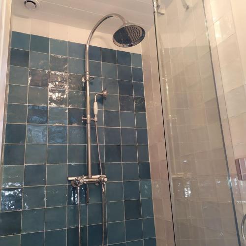 d'une douche avec du carrelage bleu et un pommeau de douche. dans l'établissement STUDIO HORTENSIA à 2 pas du port - Confortable, classé 2 étoiles, à Cancale