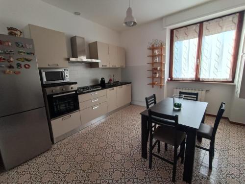 a kitchen with a table and a refrigerator and a table and chairs at B&b Lupita in Dormelletto