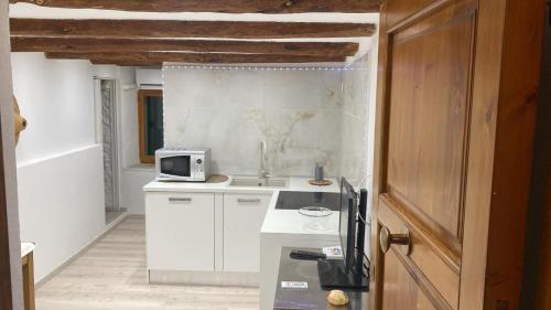 a white kitchen with a sink and a microwave at La Scogliera in Alghero