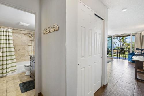 a bathroom with a toilet and a tub and a door at Island Surf 304 - Renovated, Ocean Views, Split AC in Kihei