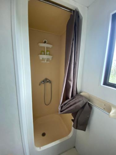 a shower with a shower curtain in a bathroom at Mobile-home en bord de mer in Pordic