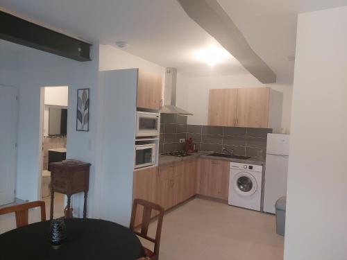 a kitchen with a table and a washer and dryer at Gîte Cabara in Cabara