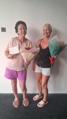 two women standing next to a wall holding flowers at RKO Villa27 - Unawatuna in Habaraduwa