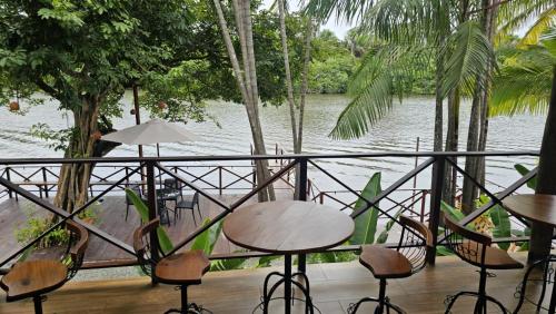 a balcony with tables and chairs next to a body of water at Pousada Casa Dunas in Barreirinhas