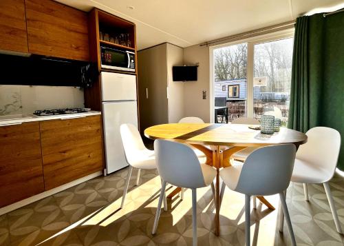 a kitchen with a wooden table and white chairs at Beach Chalet- Sauna inklusive Kinder und Hunde Willkommen in Scharbeutz