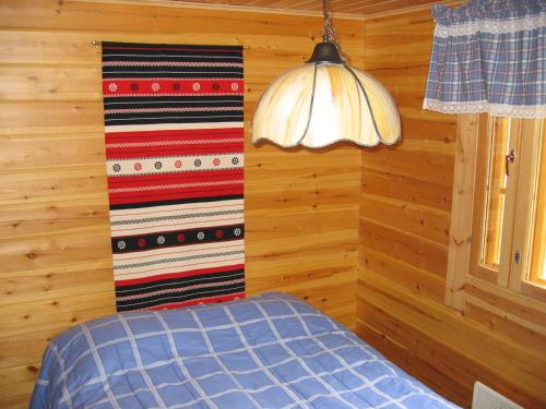 een slaapkamer met houten wanden en een bed en een lamp bij Ukonloma Härkälampi in Rovaniemi