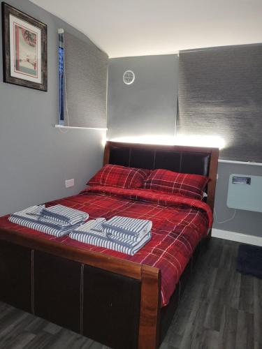 a bedroom with a bed with red sheets and a red blanket at The Nook in Great Cornard
