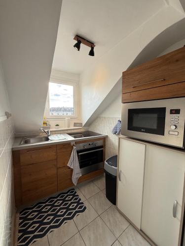 une petite cuisine avec un évier et un micro-ondes dans l'établissement Appartement au cœur du centre ville, à Saumur