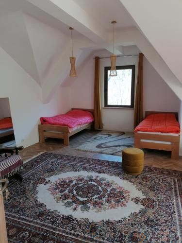 Una habitación abuhardillada con dos camas y una alfombra. en Pelister Chalet, en Bitola
