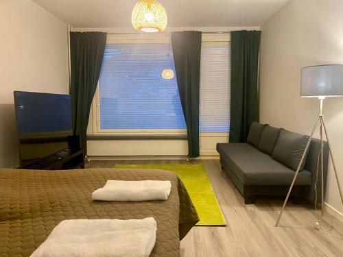 a bedroom with a bed and a couch and a window at HUTTUNEN 2 - Ihqu kaksio mahtavalla sijainnilla! in Iisalmi