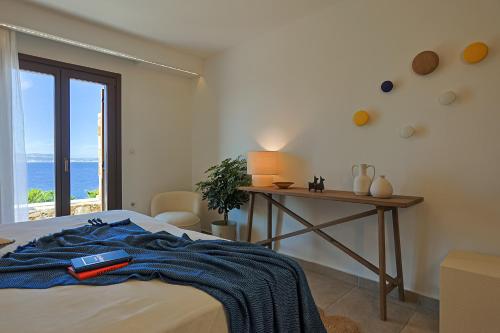 a bedroom with a bed and a table with a window at ZELION VILLA in Stelida