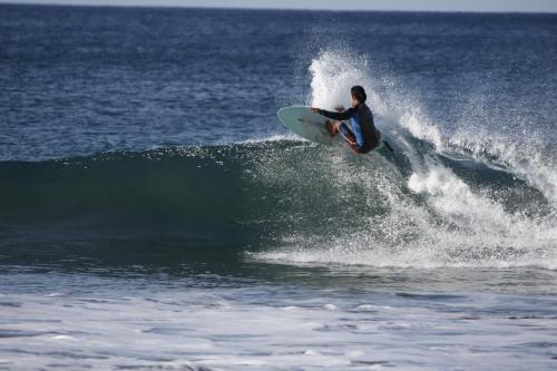 a man riding a wave on a surfboard in the ocean at Hotel Hibiscus in Playa Junquillal