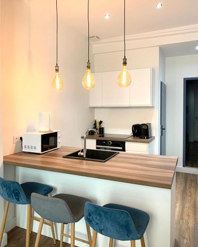 une cuisine avec un comptoir avec des chaises bleues et des lumières dans l'établissement Rotonde, 2 chambres, Air conditionné, à Aix-en-Provence