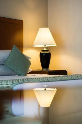 a bedroom with a bed with a lamp on it at Bangkok Palace Hotel in Bangkok