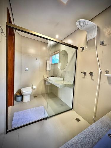 a bathroom with a glass shower with a toilet and a sink at Vila Puru - 6 apartamentos - 2 com jacuzzi e 4 sem - Café da manhã à parte in Alto Paraíso de Goiás