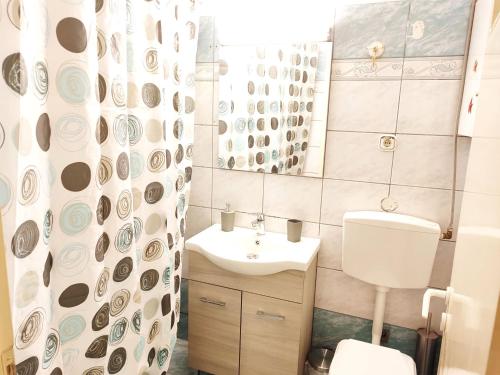 Un baño con lavabo, inodoro y espejo. en Cathrine's Apartment, en Tríkala