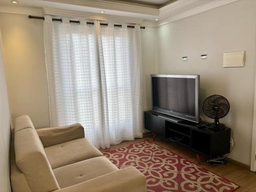 a living room with a couch and a flat screen tv at Apto 3 quartos próximo aeroporto net 500 Mb, garagem e enxoval in São José dos Pinhais