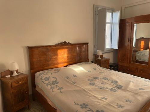 a bedroom with a bed with a wooden headboard and a mirror at Traditional house Zia Dina in Mògoro