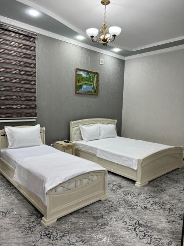 two beds in a room with two bedsitures at DUNYO Hotel in Jizzax