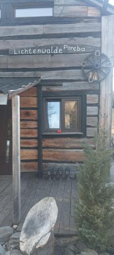 a wooden cabin with a sign on the side of it at Enklawa w Porębie in Długopole-Zdrój