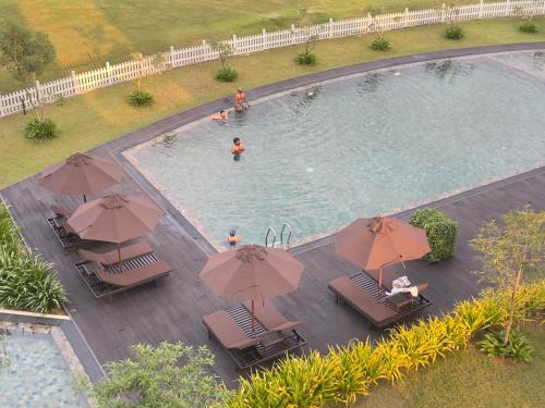 une vue aérienne d'une piscine avec chaises et parasols dans l'établissement Canterbury Golf Resort Apartment, à Piliyandala