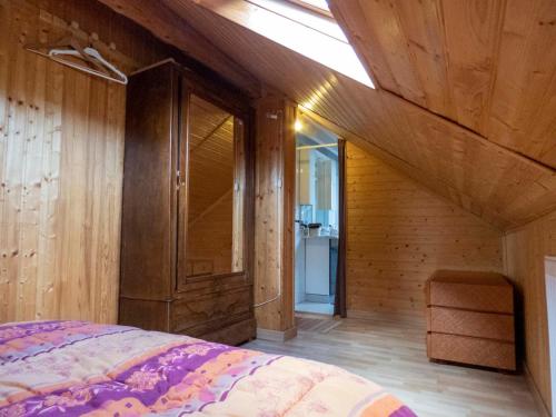 - une chambre avec un lit, des murs en bois et une lucarne dans l'établissement Maison entre lac et montagnes, à Draillant