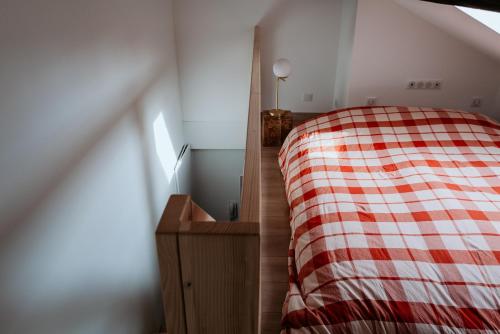 a bedroom with a bed with a red and white plaid blanket at Le Chat Léon in Chalon-sur-Saône