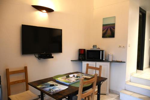 d'une salle à manger avec une table et une télévision à écran plat. dans l'établissement Villa les Lauriers, à Lioux