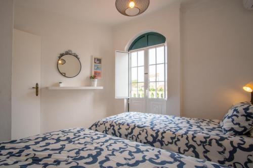 a bedroom with two beds and a window and a mirror at HAUS NUNES by Stay in Alentejo in Vila Nova de Milfontes
