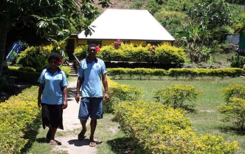 a man and a boy standing on a path in a garden at Ratu Kini Dive & Stay in Mana Island