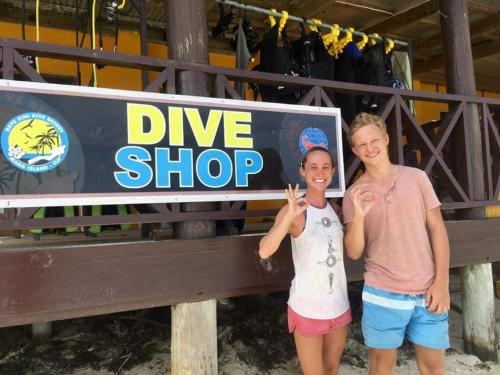 two women standing next to a dive shop sign at Ratu Kini Dive & Stay in Mana Island