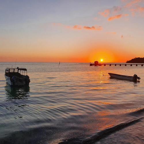 two boats sitting on the water at sunset at Ratu Kini Dive & Stay in Mana Island