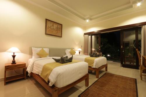 1 dormitorio con 2 camas y ventana grande en Duana Sari by Mahaputra en Ubud