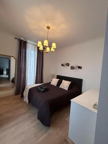 - une chambre avec un lit noir et un lustre dans l'établissement Appartement chaleureux en centre ville, à Nîmes