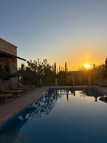 a swimming pool with the sunset in the background at Maison la chèvre By Nath & Lulu in Essaouira
