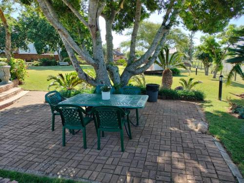 a green table and chairs on a brick patio at Little Tree Loft in Uitenhage